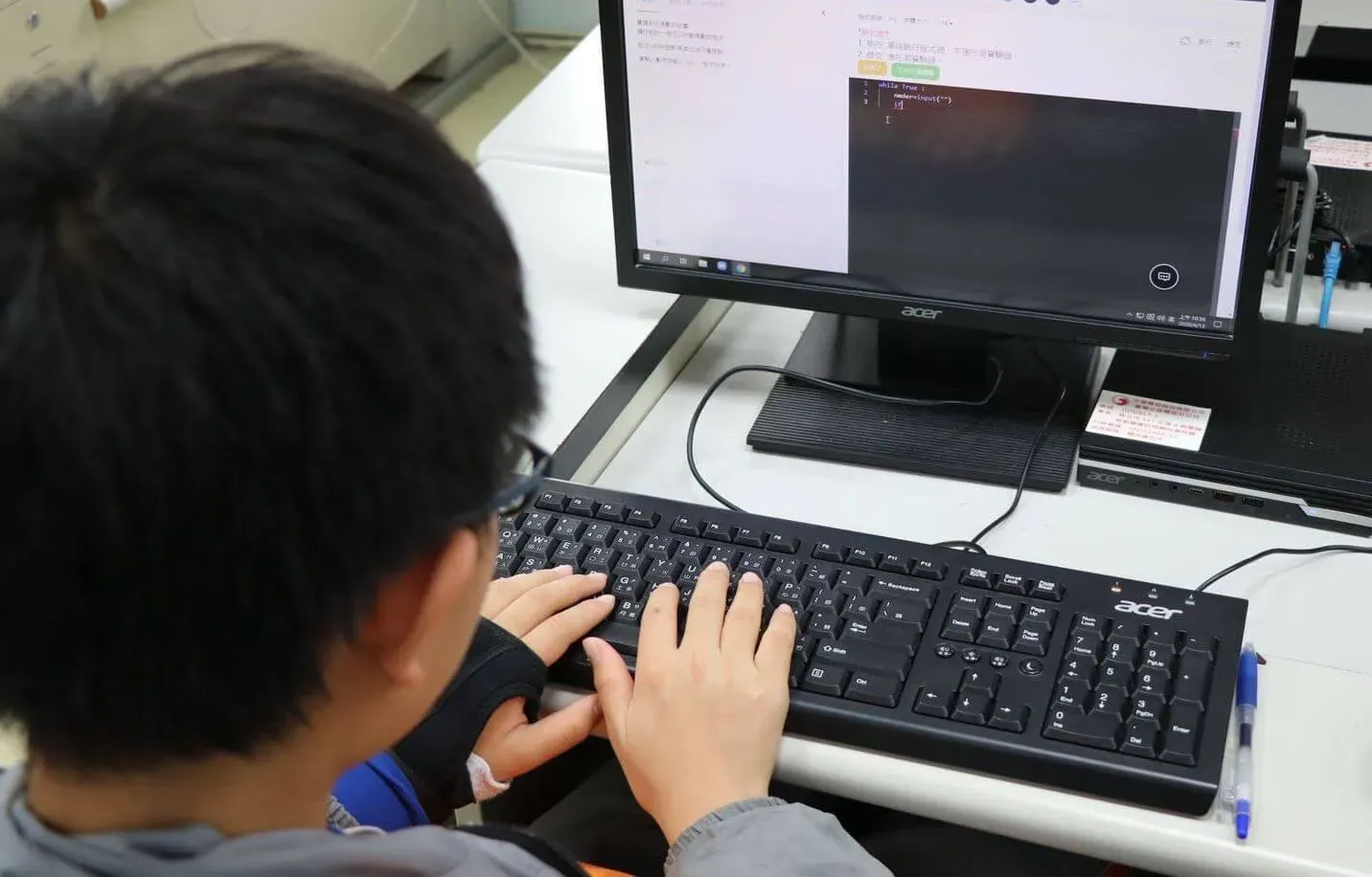 一個中學生對著電腦練習程式習題